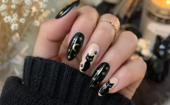 Black cat nails with glossy black polish, cute cat artwork, gold stars, moon details, and elegant Halloween-inspired nail design on real hands.