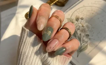 woman's hand featuring elegant Virgo-inspired almond-shaped nails in soft sage green and nude tones with delicate gold botanical details and subtle constellation-inspired accents