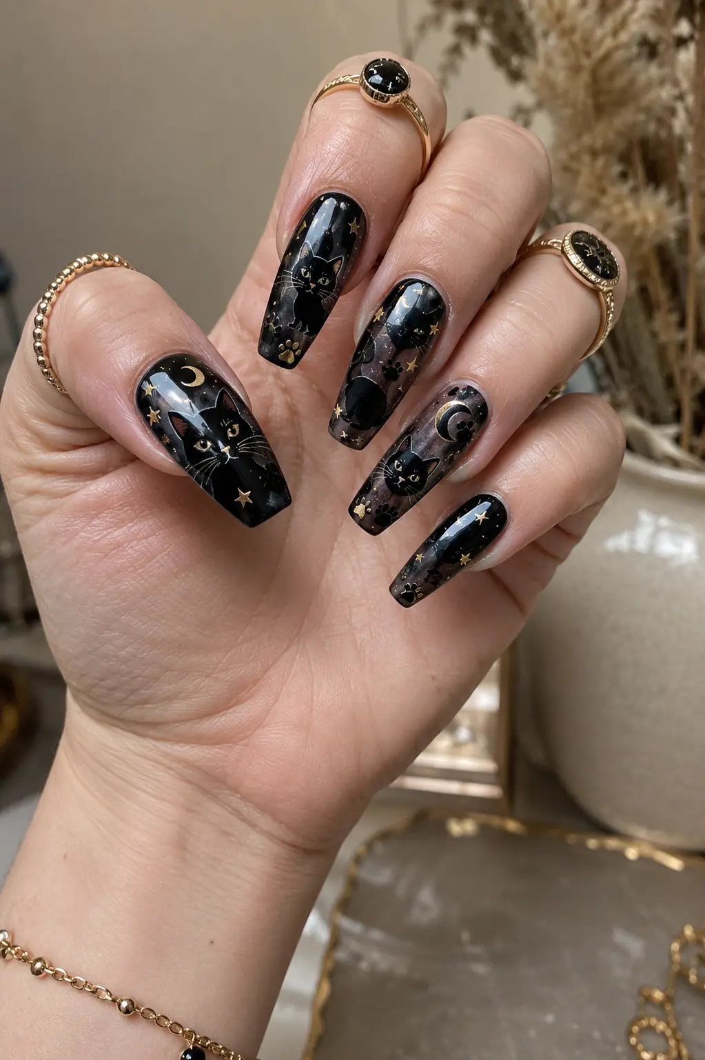 Black cat acrylic nails with glossy finish, cute cat artwork, paw prints, moon accents, gold stars, and elegant spooky nail details.