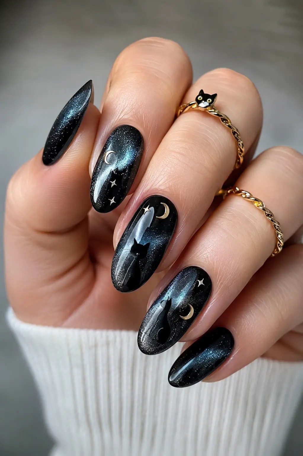 Black cat eye nails with glossy magnetic polish, moon and star accents, detailed cat nail art, and elegant rings in a luxury manicure style.