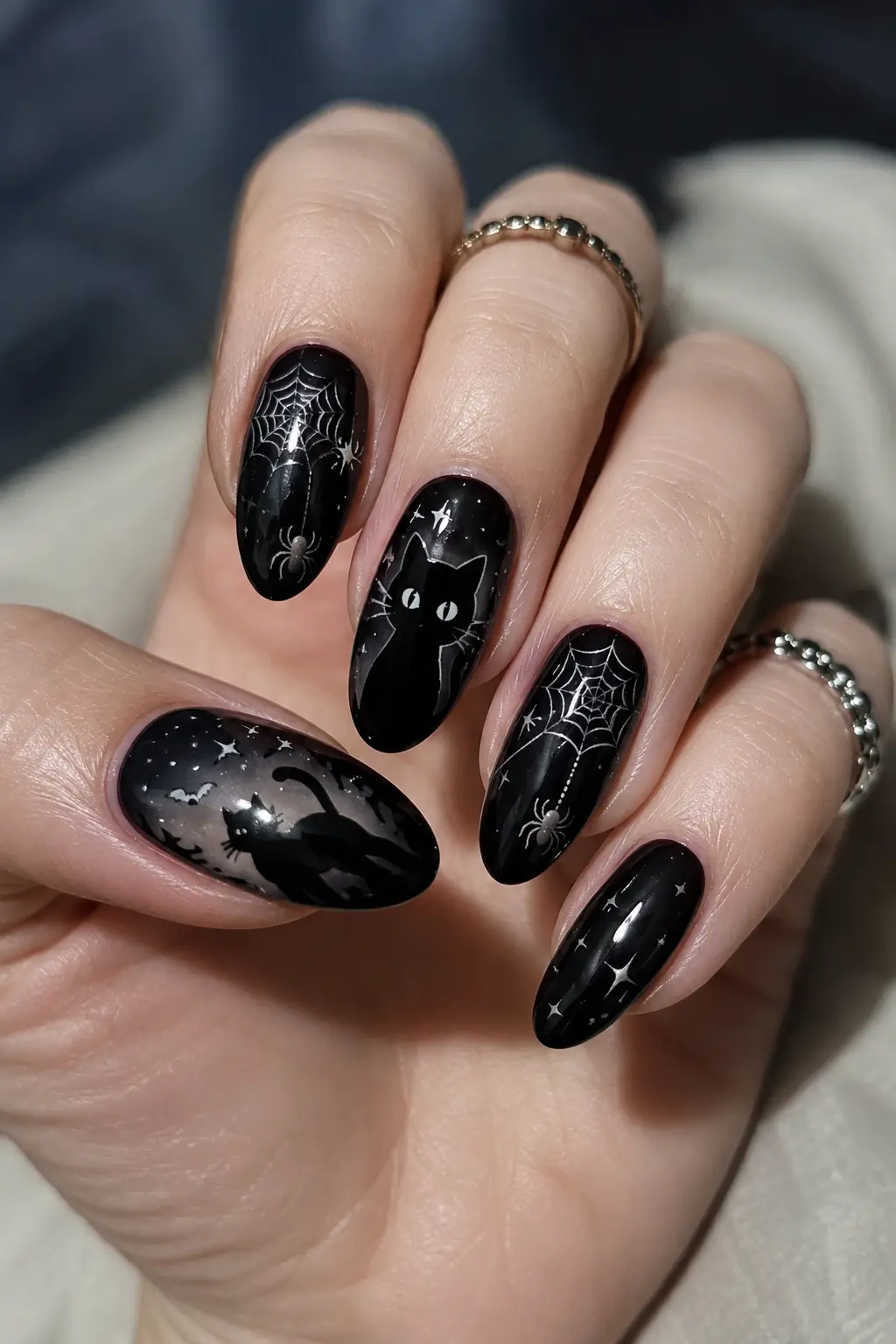 Black cat spider web nails with glossy dark polish, cute cat artwork, spooky web details, stars, and elegant Halloween manicure design.