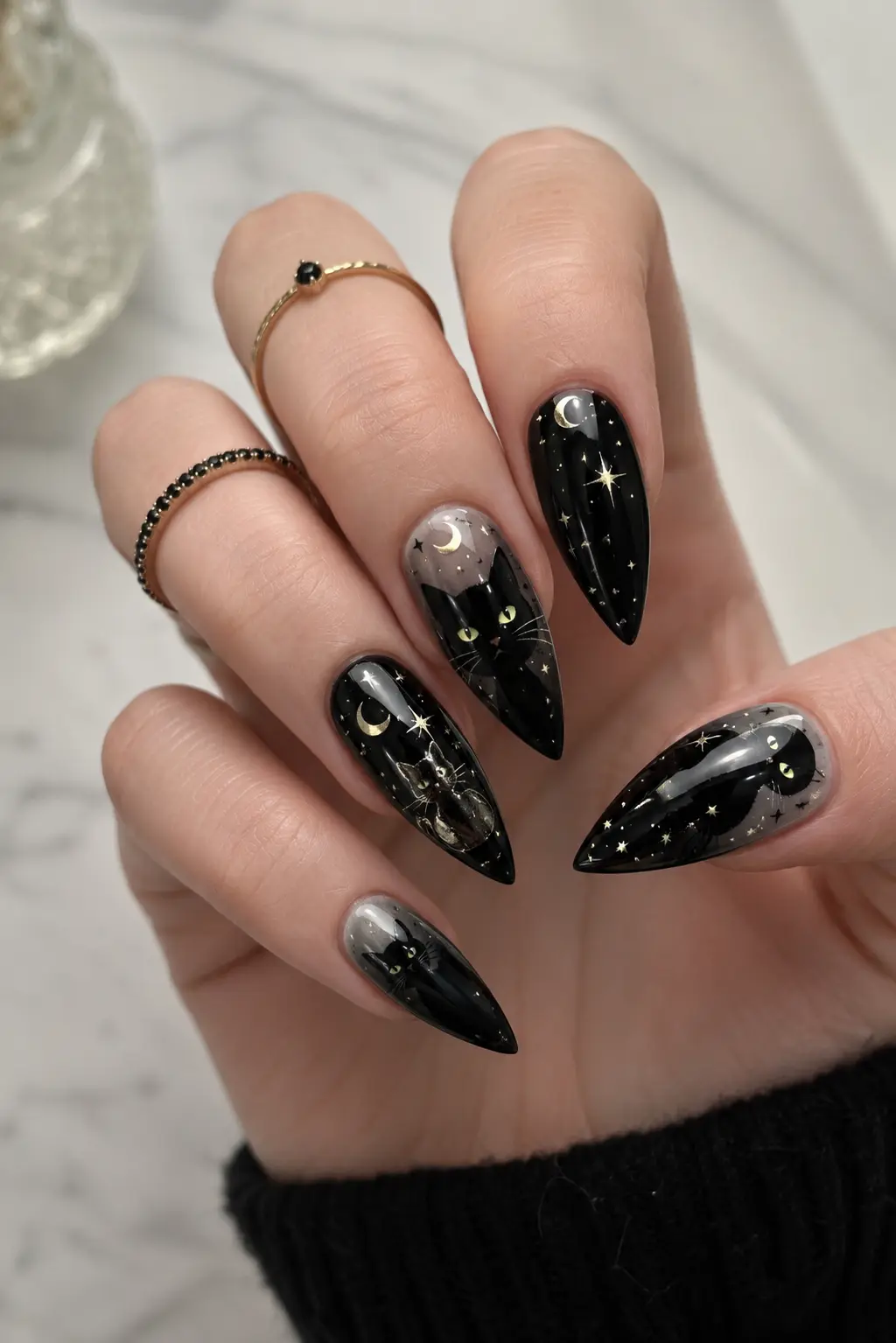 Sharp black cat stiletto nails with glossy finish, glowing cat eyes, moon accents, tiny stars, and spooky celestial nail art design.