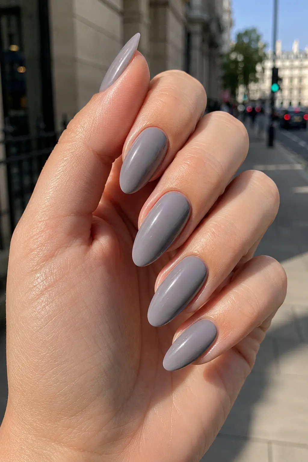 woman's hand with glossy soft gray almond-shaped nails featuring a single fine silver metallic stripe accent,