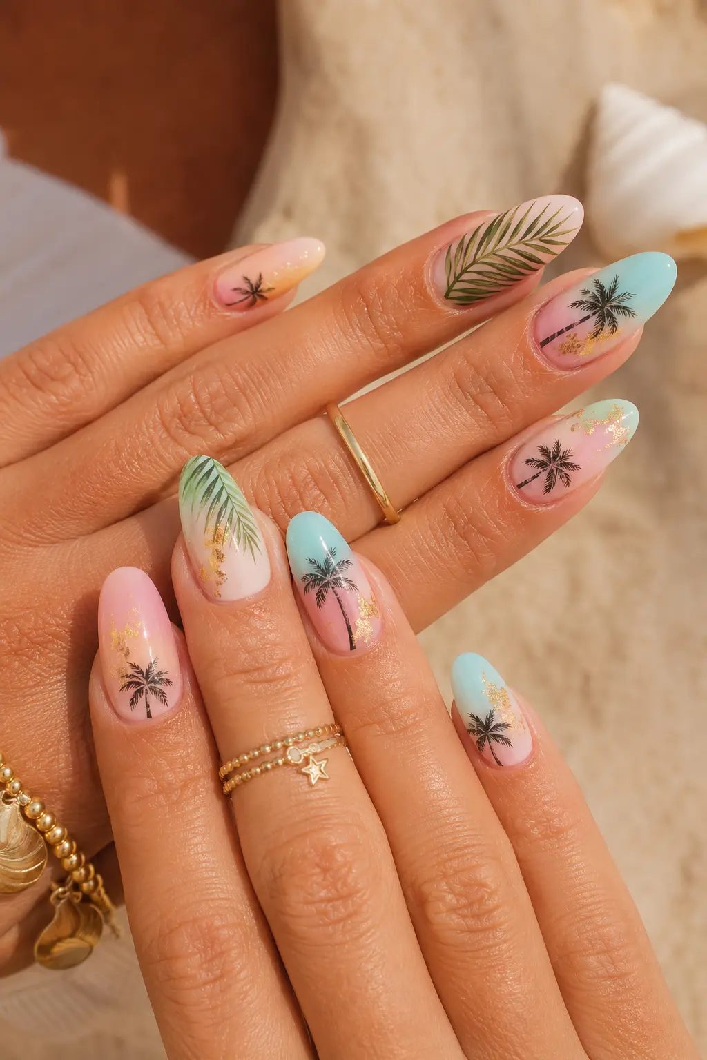 women’s hands featuring tropical palm tree summer nail designs with pastel gel colors, almond-shaped nails, glossy finish, palm leaf art, gold jewelry, and beach-inspired manicure style.